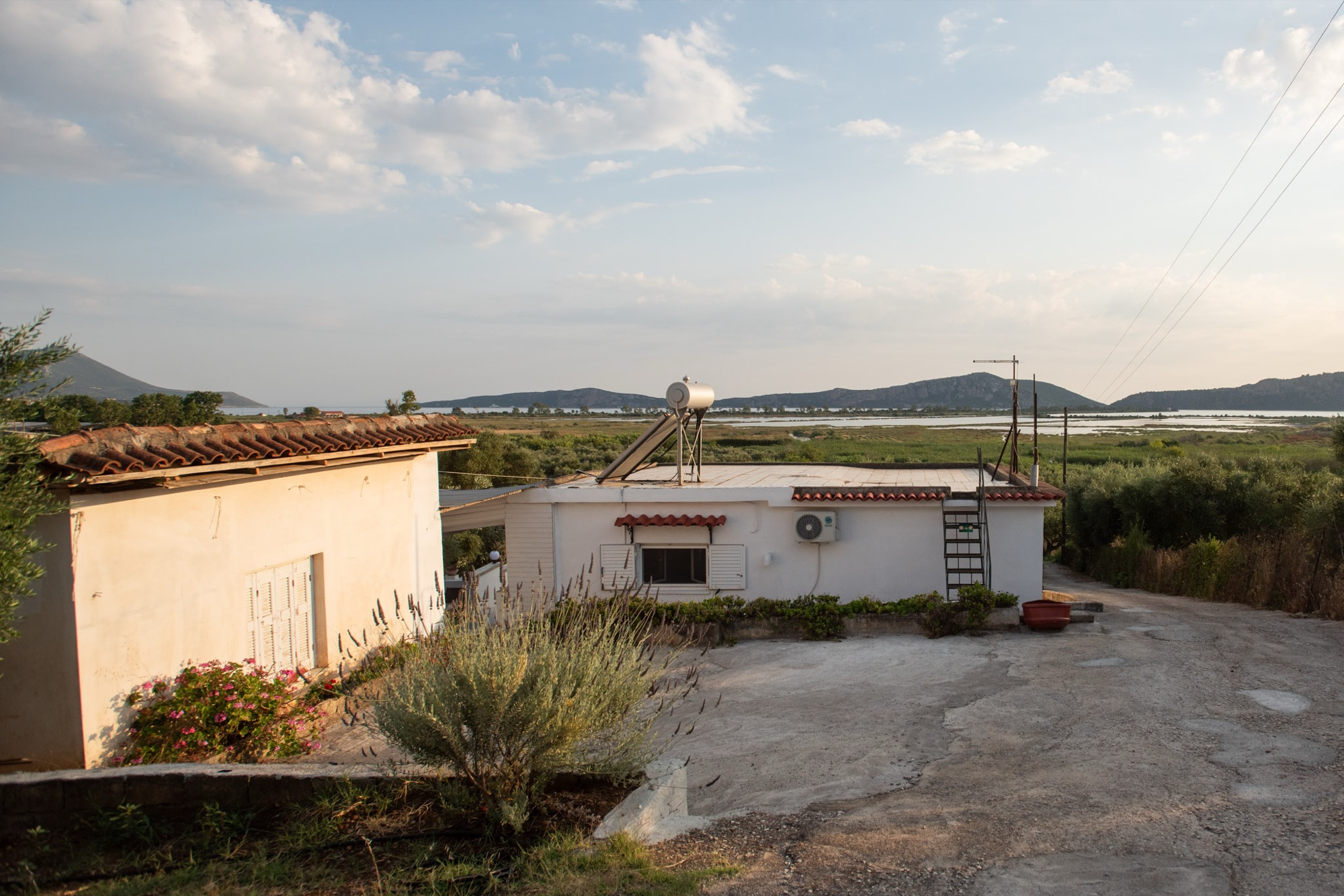 Lake House exterior at golden hour, overlooking Gialova Lagoon and the Navarino Bay hills